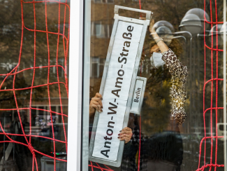 Two persons installing a historical street sign in the project space of Dekoloniale Berlin.