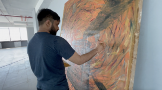 A man painting on a canvas in a gallery space
