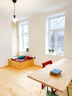 A desk and seating structure in a white room with a wooden floor.
