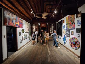 a group of people in an exhibition space watching colourful artworks on the wall