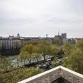 view from a balcony over the city of Paris, with trees the Seine river and its old buildings on the riverside