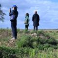 three people standing in a natural lanscapes with grass and trees