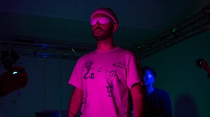 Man standing in a performing arts studio in coloured lights.