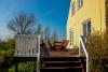 Sunny terrace with wooden deck chairs adjacent to a yellow wooden house on the Danish countryside