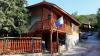 A wooden traditional house in a hilly and rural environment next to a climbing road