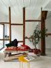 A wooden structure of beams, a plant, a seating structure and a coffee table in a room painted white.
