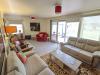 A room with beige sofas and a coffee table with windows overlooking a garden