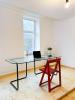 A glass working desk with red wooden chair in a white room with a wooden floor.