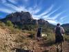 People in outdoor gear climbing an arid rock. 