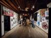 a group of people in an exhibition space watching colourful artworks on the wall
